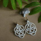 Close-up of white Mizuhiki turtle knot earrings (Kamenoko-musubi), handmade by Itookasi for luck and longevity.