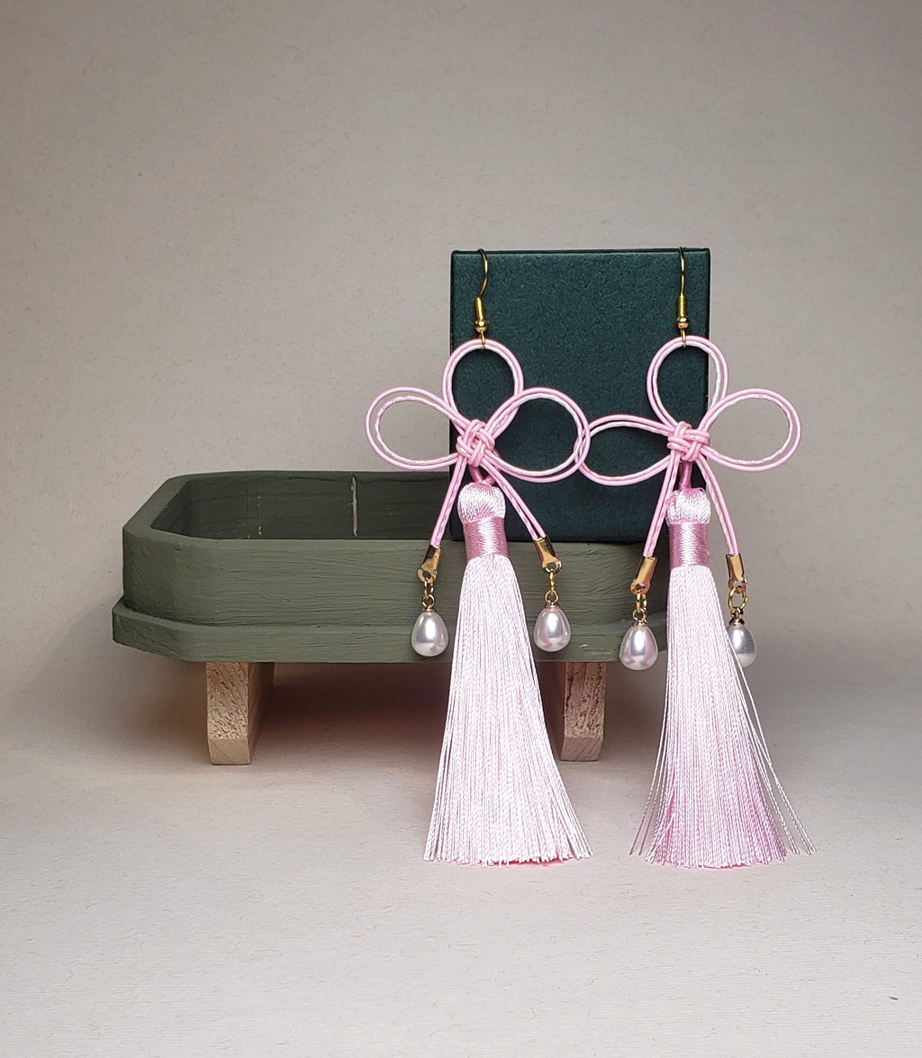 Close-up of pink and white Mizuhiki Kano Knot earrings featuring a tassel, handmade by itookasi for eternal bonds.