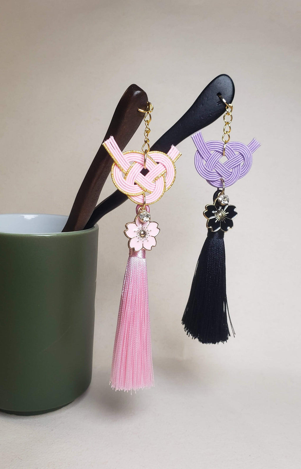 Close-up of pink and purple Japanese Kanzashi hair ornament featuring red Mizuhiki Awaji knots with a tassel and Sakura charm. Handmade by Itookasi.