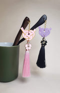 Close-up of pink and purple Japanese Kanzashi hair ornament featuring red Mizuhiki Awaji knots with a tassel and Sakura charm. Handmade by Itookasi.