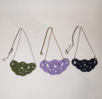 Close-up of a black, green and purple Mizuhiki pine knot necklace, handmade by Itookasi. The pine knot (Matsu-musubi) symbolises longevity and happiness.
