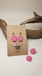 Close-up of earrings with pink plum blossom knot and cherry blossom charms, handmade by itookasi for eternal bonds.