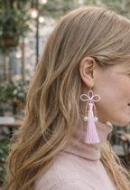 Close-up of pink Mizuhiki Kanou knot earrings featuring a pink tassel and pearl, worn by a model, handmade by itookasi. 